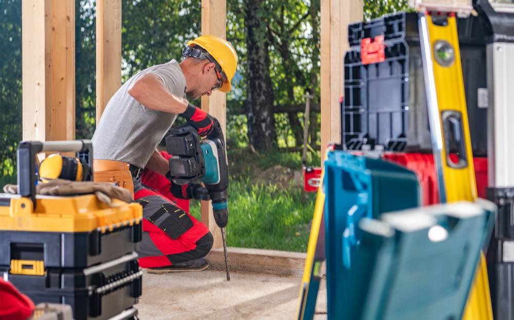 Homme perçant le béton avant d'utiliser un scellement chimique pour fixer son support