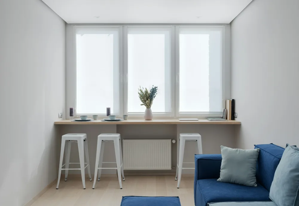 Intérieur réel d’une maison container aménagée avec un canapé bleu, illustrant la contrainte de largeur