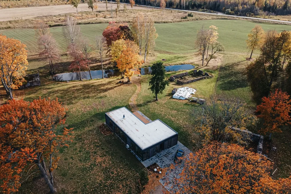 Maison en containers avec toit plat implantée sur un vaste terrain arboré automnal