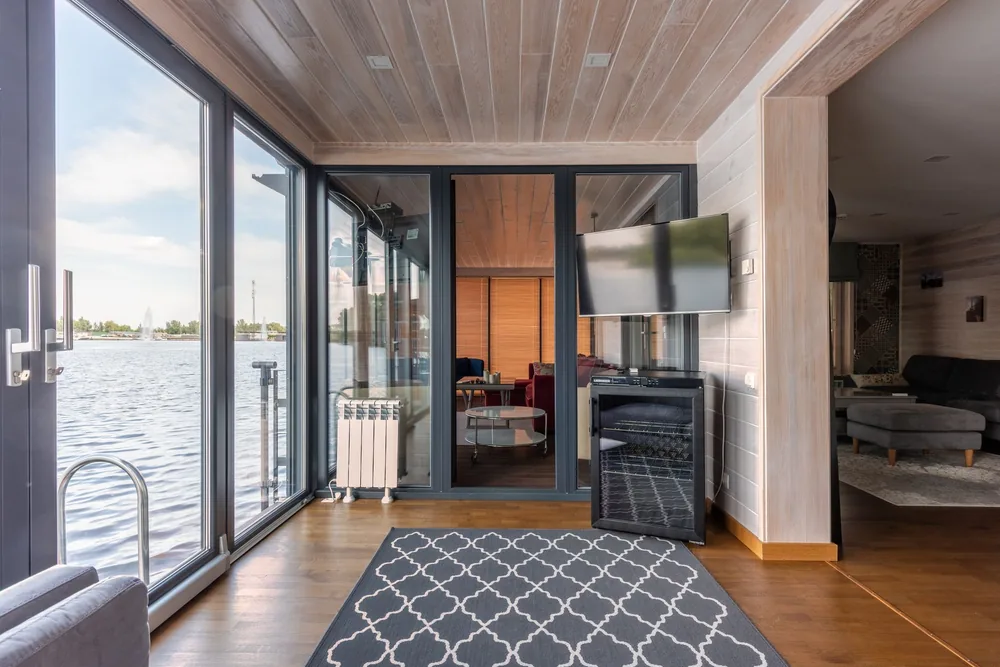 Intérieur d'une maison container pour se faire un avis avec une pièce de vie avec baie vitrée ouvrant sur un lac